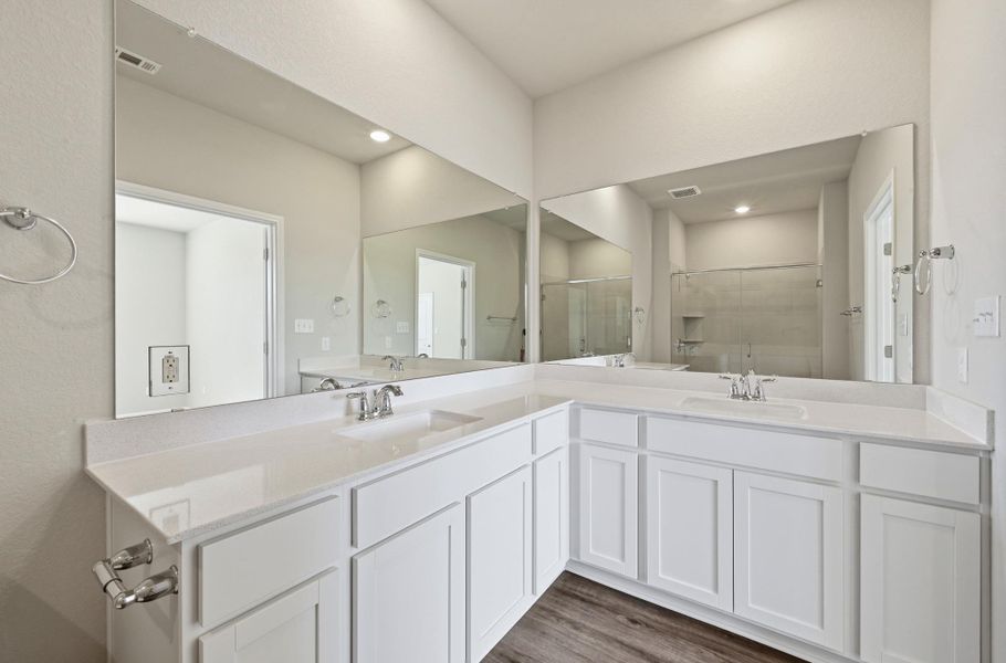 Bathroom vanity featuring dual undermount sinks, quartz countertops, white cabinetry, and a large wall-mounted mirror Bathroom vanity featuring dual undermount sinks, quartz countertops, white cabinetry, and a large wall-mounted mirror