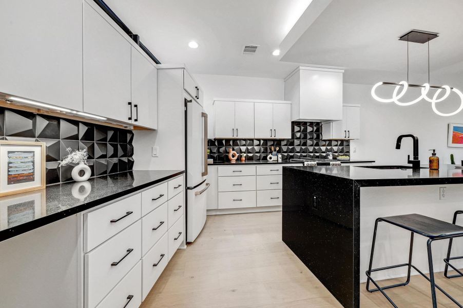 Kitchen featuring a breakfast bar area, dark stone countertops, hanging light fixtures, tasteful backsplash, and recessed lighting