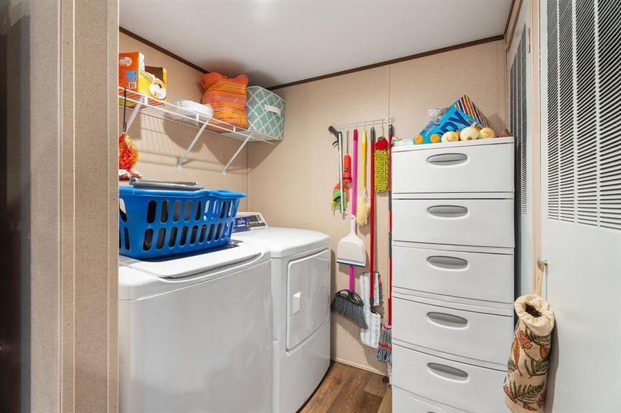 Clothes washing area featuring wood finished floors, laundry area, separate washer and dryer, a heating unit, and crown molding Clothes washing area featuring wood finished floors, laundry area, separate washer and dryer, a heating unit, and crown molding