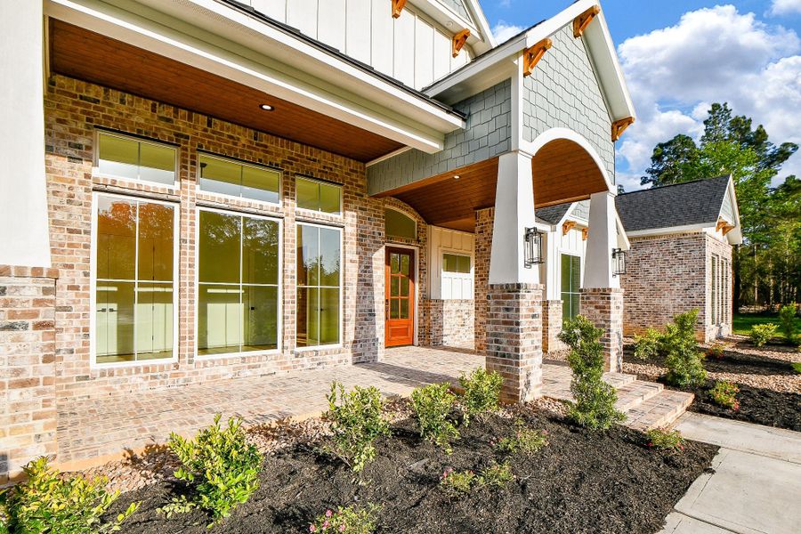 A covered front porch with rich wood accents and statement lighting invites you in with warmth and sophistication. A covered front porch with rich wood accents and statement lighting invites you in with warmth and sophistication.
