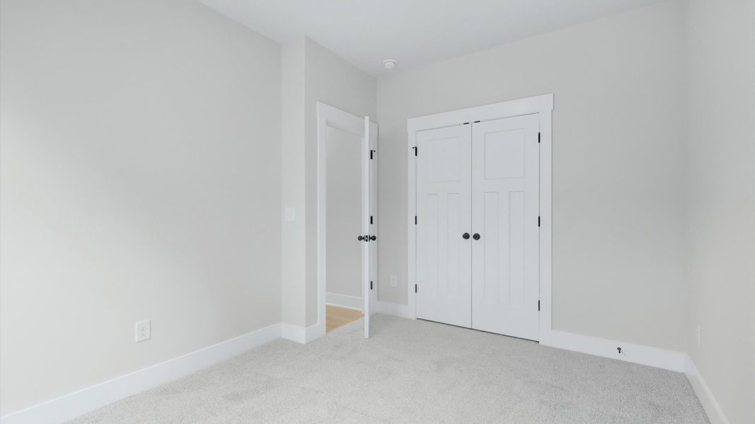 Elegant bedroom retreat featuring soft carpeting and a thoughtfully designed walk-in closet