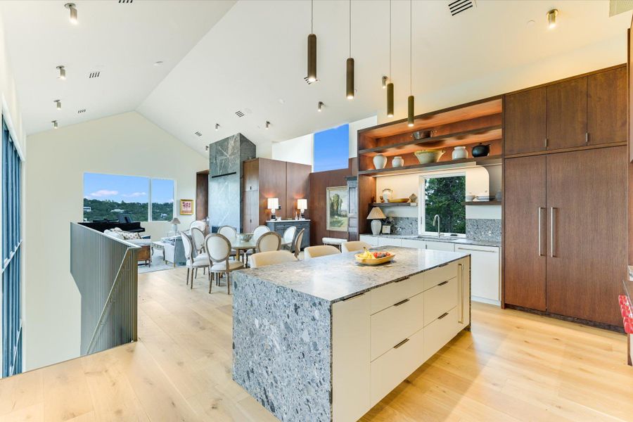 Kitchen with open shelves, light stone countertops, high vaulted ceiling, modern cabinets, and light wood finished floors