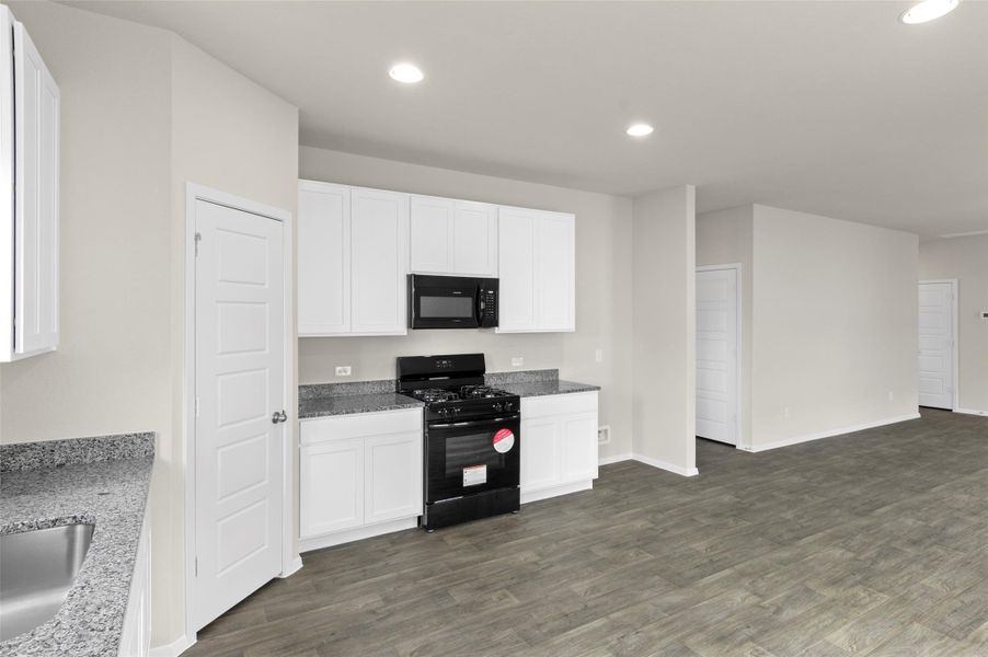 Kitchen with black appliances, recessed lighting, dark wood-type flooring, white cabinets, and light stone counters Kitchen with black appliances, recessed lighting, dark wood-type flooring, white cabinets, and light stone counters