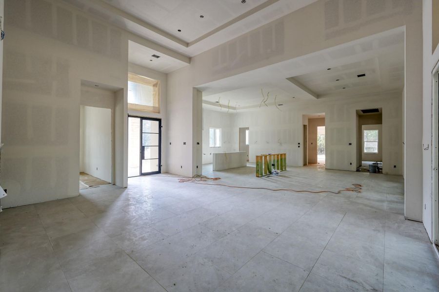 The view from the great room into the kitchen and dining room reinforces the home’s open design, where natural light and connected living spaces create a welcoming, organic flow with 24 x 48 inch tiles throughout for open flow.