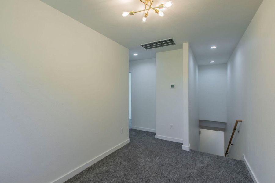 Unfurnished room with dark carpet, recessed lighting, and a chandelier