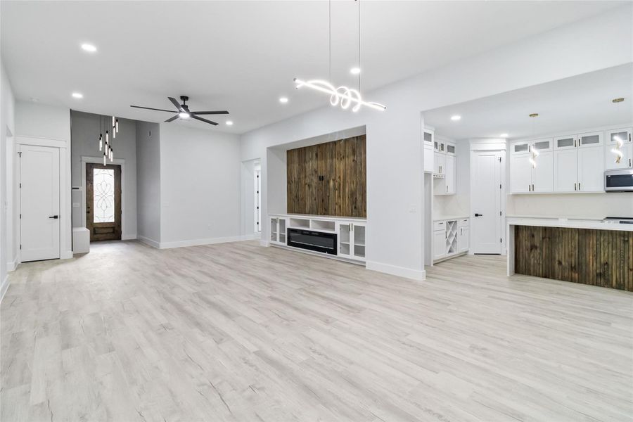 Unfurnished living room featuring light wood-style flooring, a ceiling fan, and recessed lighting