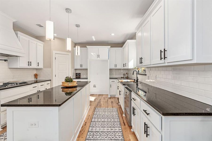 Kitchen with white cabinets, light hardwood / wood-style floors, and tasteful backsplash