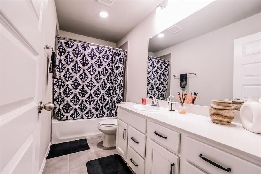 Full bathroom with tile patterned flooring, shower / bath combo, vanity, and toilet