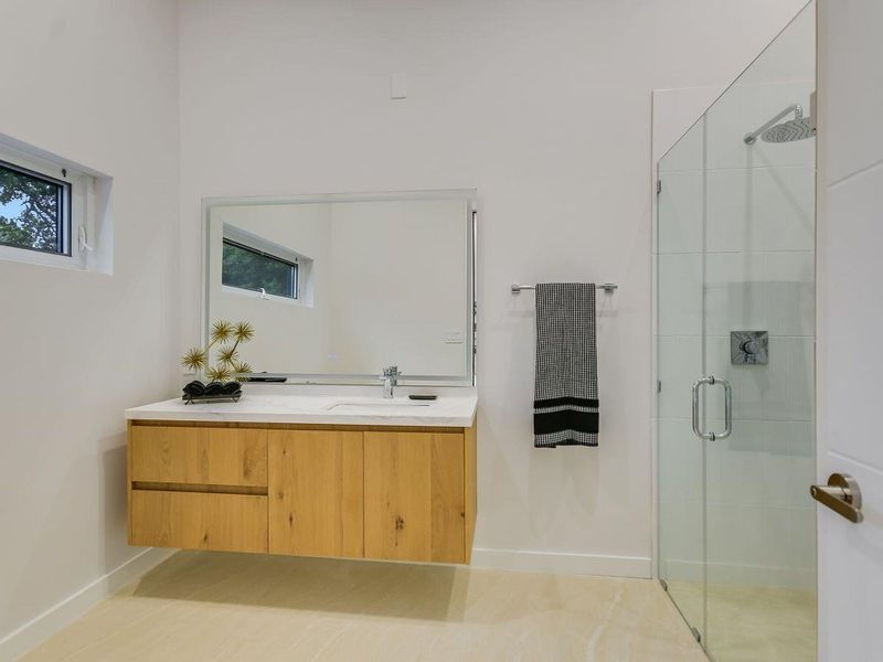 A well-lit primary bathroom features a floating vanity, modern fixtures, and a spacious glass-enclosed shower. A well-lit primary bathroom features a floating vanity, modern fixtures, and a spacious glass-enclosed shower.