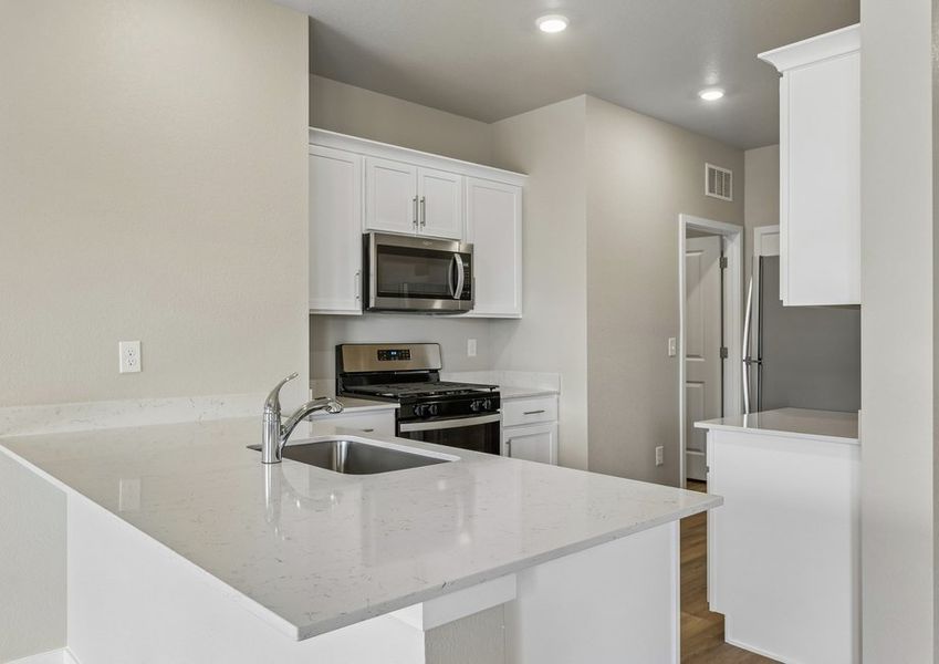 The kitchen has stainless steel appliances and plank flooring.