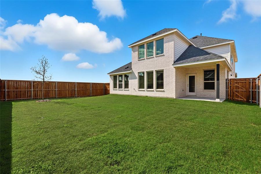 Rear view of house with roof with shingles, brick siding, a patio, a fenced backyard, and a gate Rear view of house with roof with shingles, brick siding, a patio, a fenced backyard, and a gate