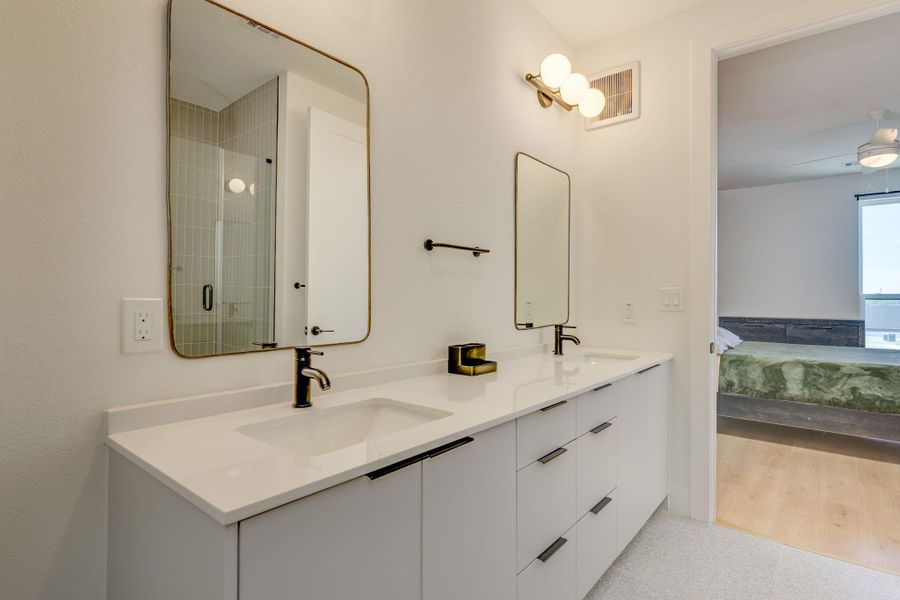 Modern bathroom featuring a dual vanity with white countertops, matte black faucets, and rectangular mirrors