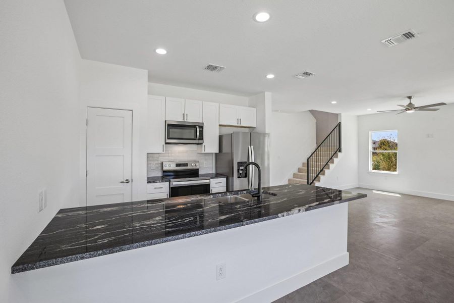 Gleaming stone countertops anchor this contemporary culinary space adjoining the main living areas.