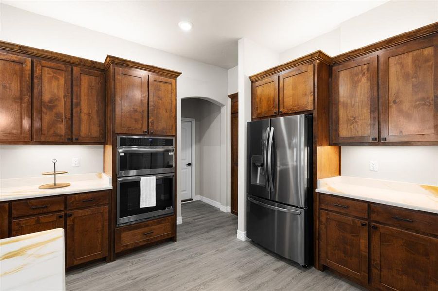 Kitchen with appliances with stainless steel finishes, arched walkways, and light wood-style floors