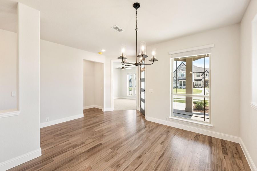 Dining room with hardwood floors, black chandelier, and large window overlooking neighborhood Dining room with hardwood floors, black chandelier, and large window overlooking neighborhood