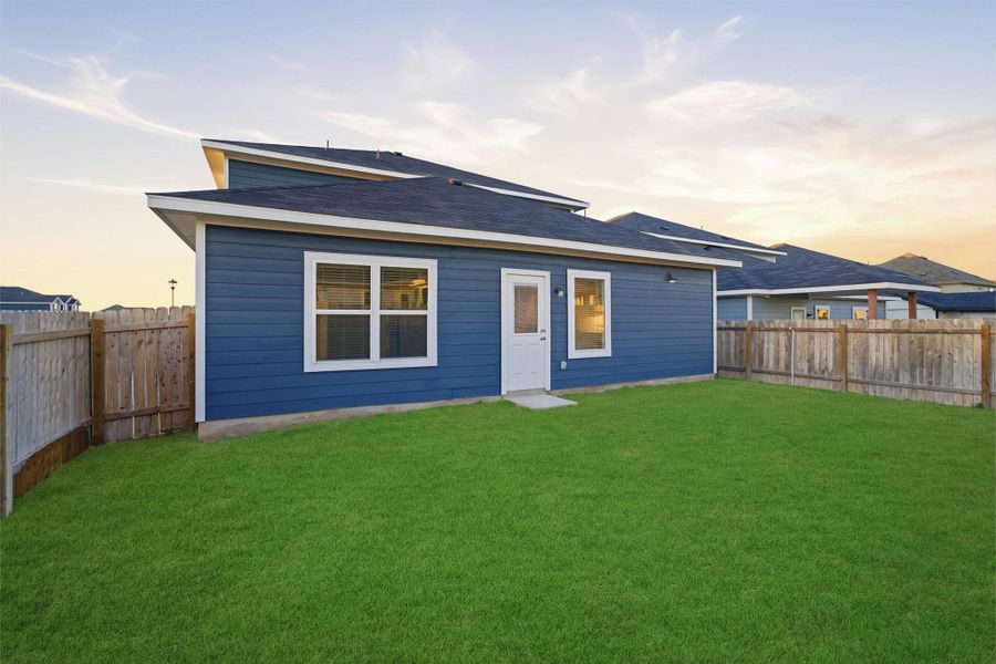 Back of property at dusk with a fenced backyard