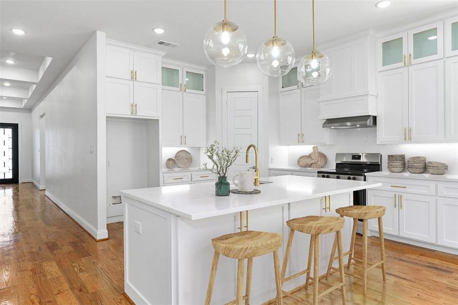 Kitchen with light hardwood / wood-style floors, a center island with sink, white cabinets, stainless steel range oven, and sink