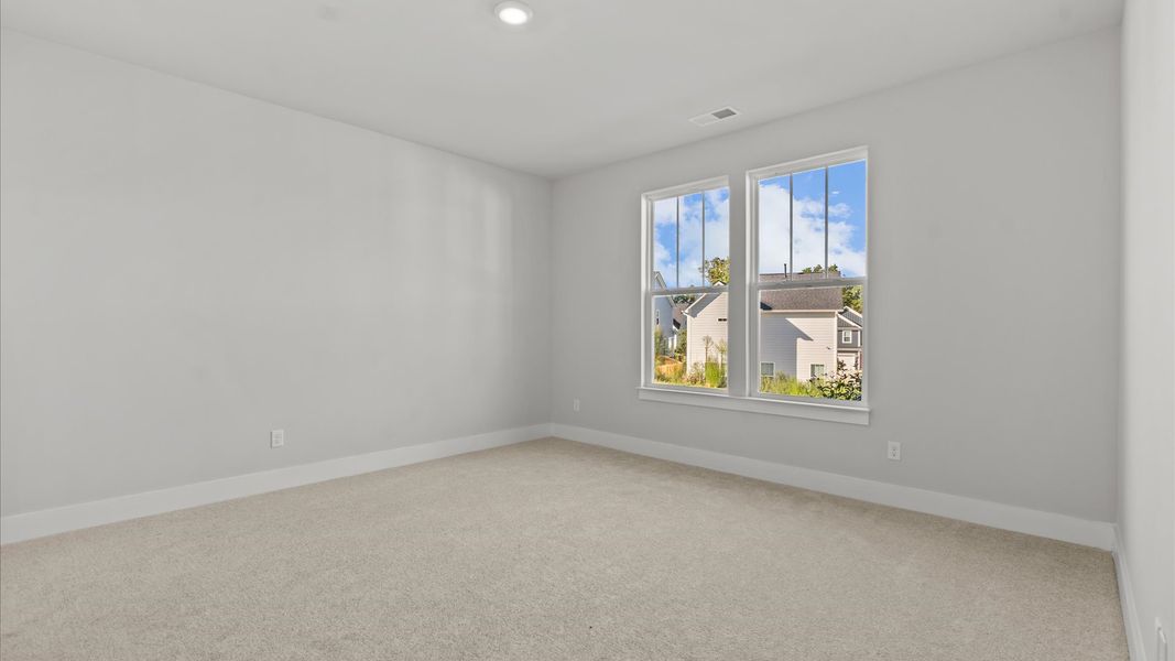 Highly functional bedroom with large windows, carpeted flooring, and tasteful finishes throughout