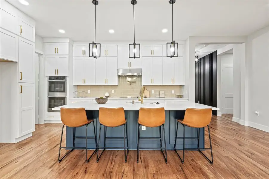 Kitchen featuring under cabinet range hood, double oven, backsplash, white cabinets, and recessed lighting Kitchen featuring under cabinet range hood, double oven, backsplash, white cabinets, and recessed lighting
