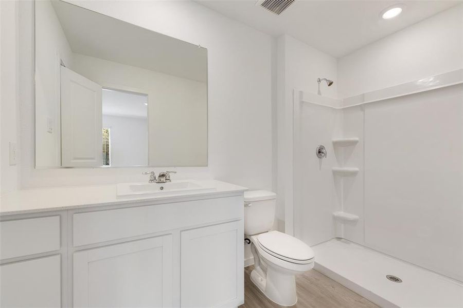 Bathroom featuring hardwood / wood-style floors, vanity, toilet, and walk in shower