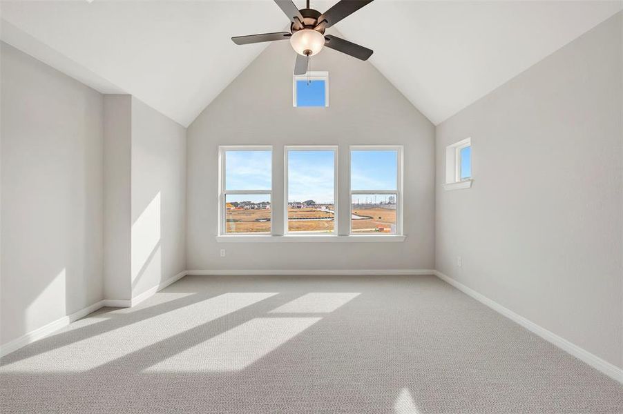Spare room with carpet flooring, ceiling fan, and vaulted ceiling