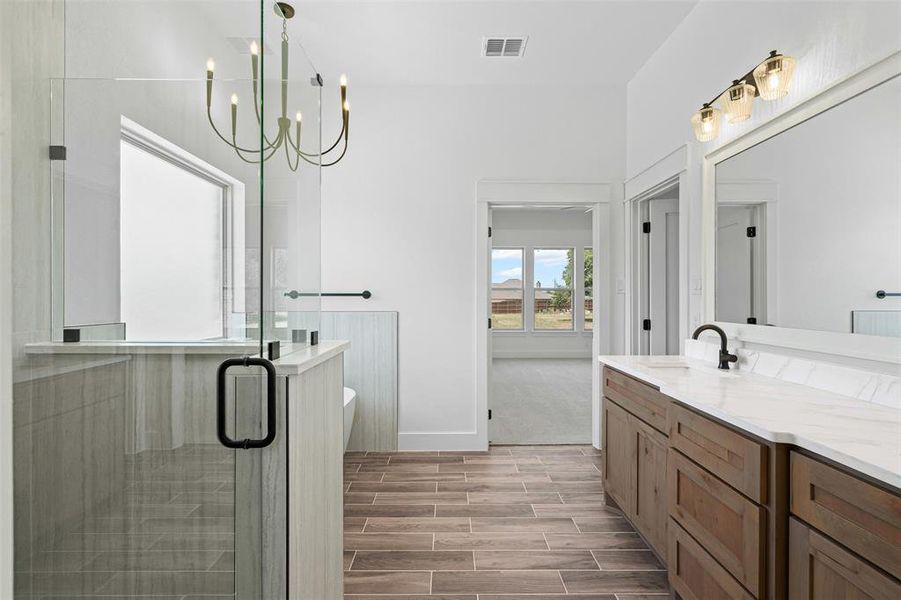 Bathroom featuring vanity, a freestanding bath, a stall shower, wood tiled floors, and a chandelier Bathroom featuring vanity, a freestanding bath, a stall shower, wood tiled floors, and a chandelier