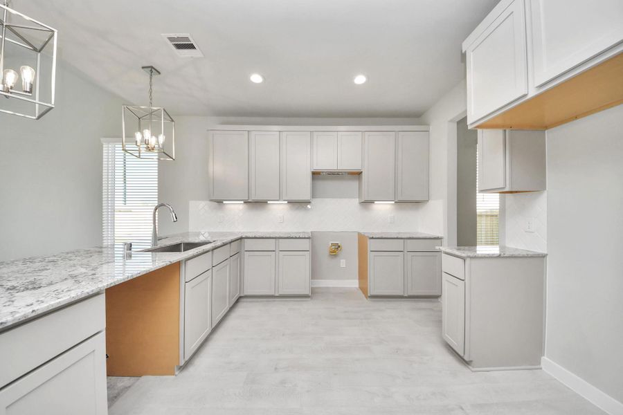 The kitchen is a culinary haven, featuring granite countertops, a tile backsplash, stainless steel appliances, 42” upper cabinets, and undercabinet lighting. Sample photo of completed home with similar floor plan. Actual colors and selections may vary.