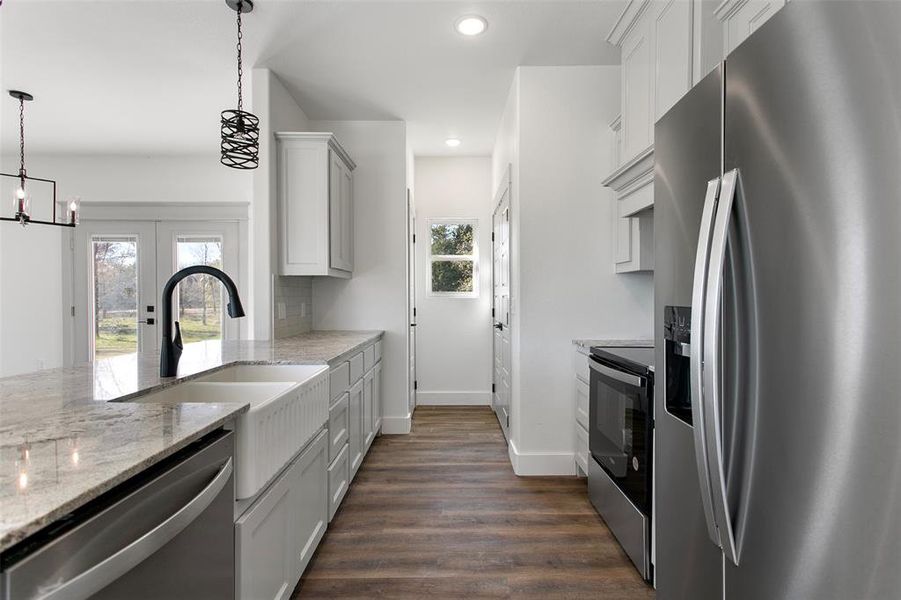 Kitchen featuring appliances with stainless steel finishes, white cabinetry, an inviting chandelier, and hanging light fixtures