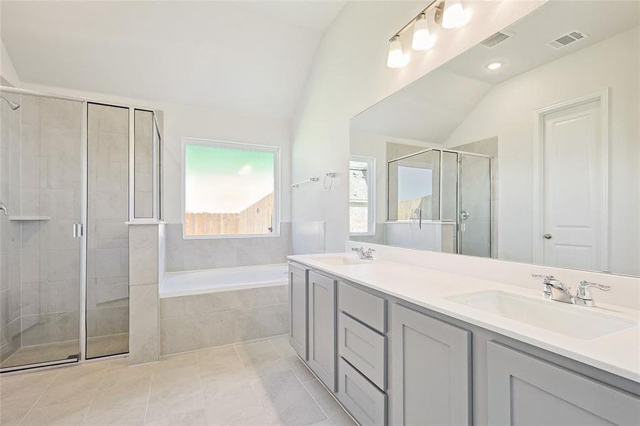 Bathroom with tile patterned flooring, shower with separate bathtub, lofted ceiling, and vanity