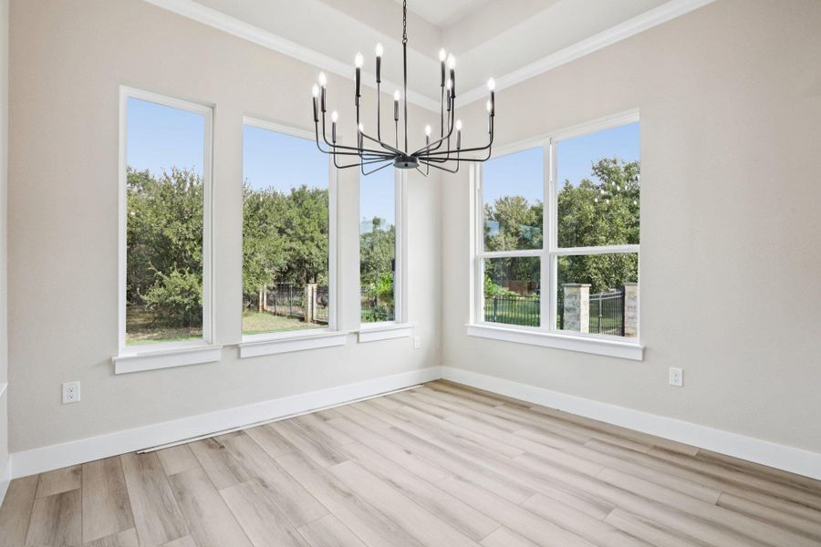 Unfurnished dining area with healthy amount of natural light, a chandelier, light wood-style flooring, and ornamental molding