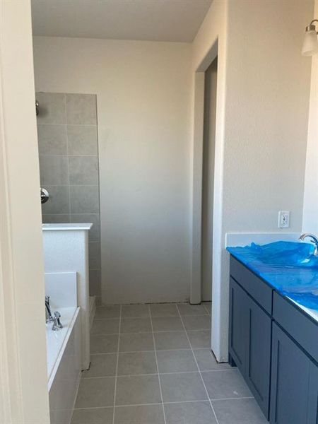 Bathroom featuring light neutral wall paint, square tile flooring, a built-in bathtub with chrome fixtures, and a shower with light grey tile surround
