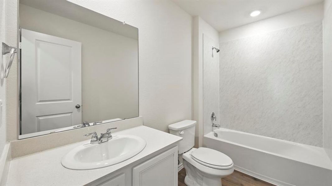 Bathroom featuring a single vanity with an integrated sink, polished chrome faucet, and a large wall-mounted mirror Bathroom featuring a single vanity with an integrated sink, polished chrome faucet, and a large wall-mounted mirror