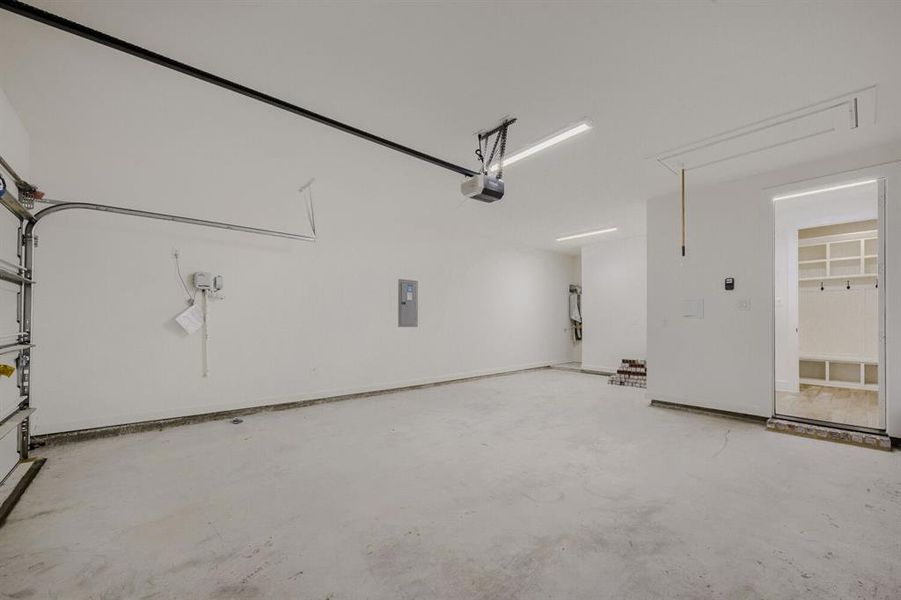 Spacious garage with an automatic door opener, concrete flooring, and bright overhead lighting