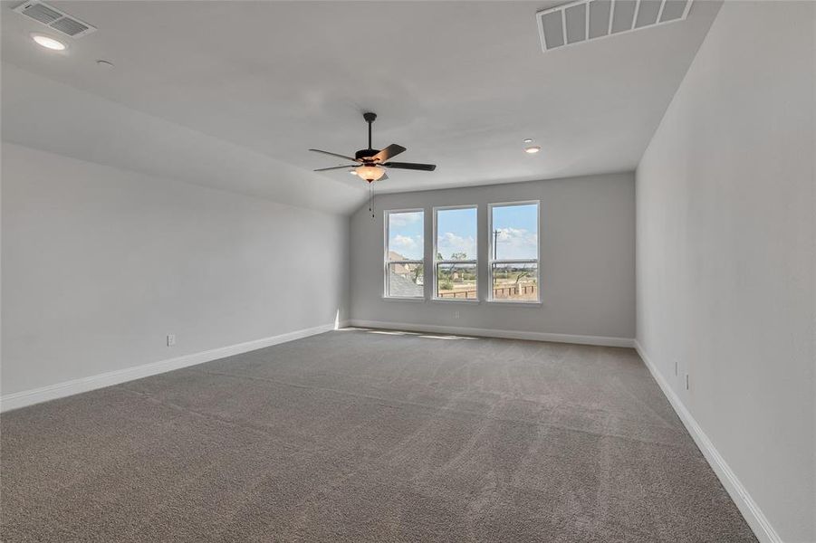 Empty room with lofted ceiling, carpet, and ceiling fan