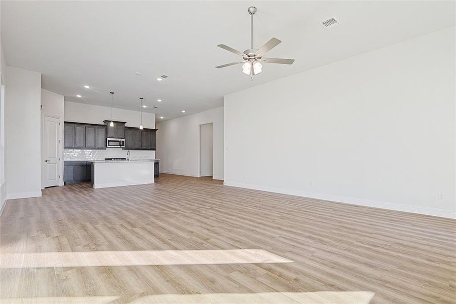 Unfurnished living room with ceiling fan and light hardwood / wood-style flooring