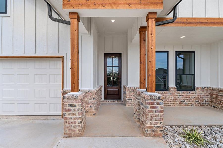 View of exterior entry featuring a porch and a garage