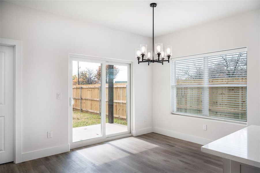 Unfurnished dining area featuring an inviting chandelier and dark hardwood / wood-style floors