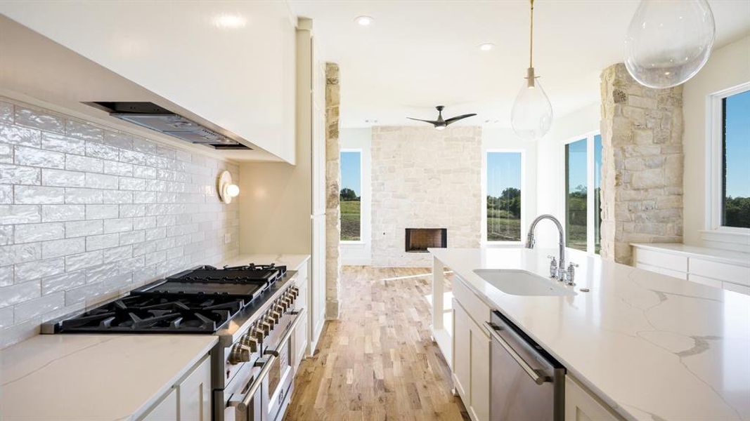 Kitchen featuring light stone countertops, sink, appliances with stainless steel finishes, and hanging light fixtures