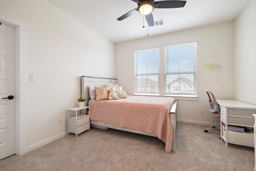 Room featuring neutral carpeting, a ceiling fan with integrated lighting, and two windows with horizontal blinds