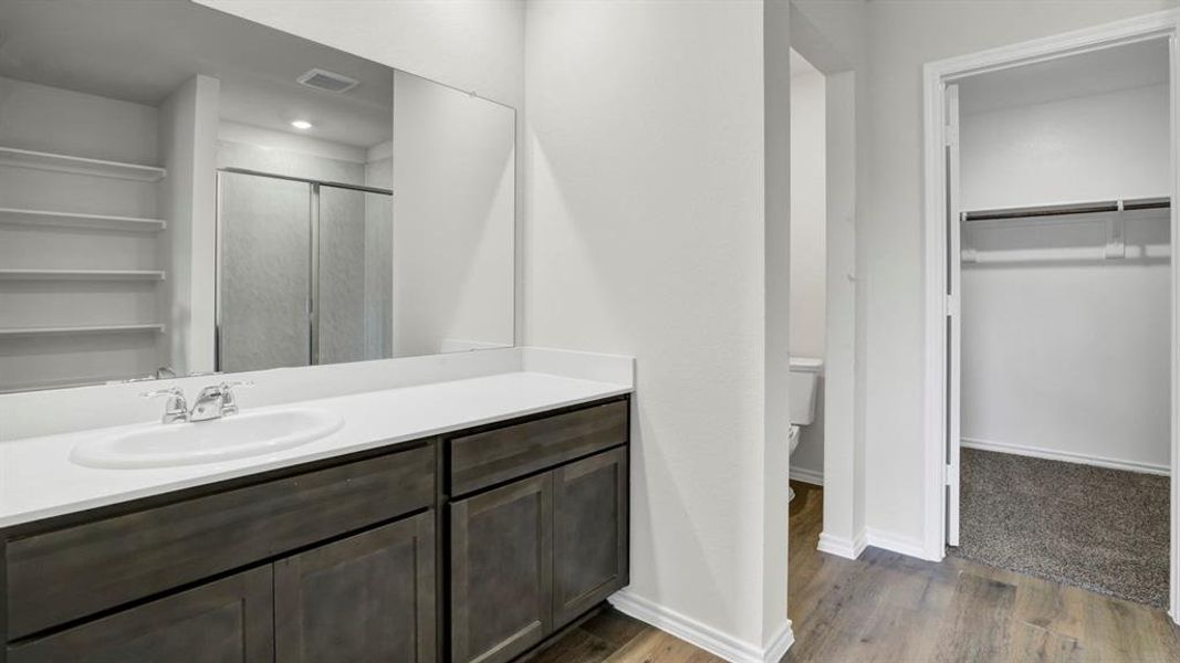 Bathroom featuring a double vanity with an integrated sink, dark wood-finish cabinetry, and a large wall-mounted mirror