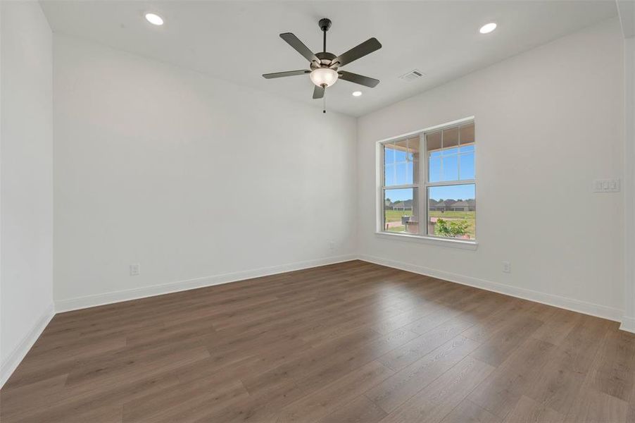 Room featuring wood-finish flooring, recessed lighting, a ceiling fan with light, and a large window overlooking the exterior Room featuring wood-finish flooring, recessed lighting, a ceiling fan with light, and a large window overlooking the exterior