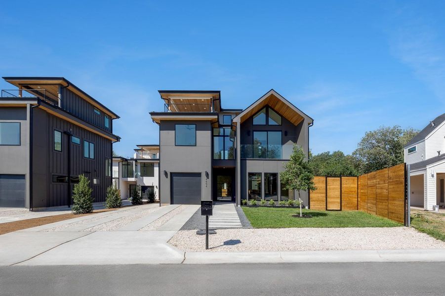 Contemporary house featuring concrete driveway, a balcony, a garage, a front lawn, and stucco siding Contemporary house featuring concrete driveway, a balcony, a garage, a front lawn, and stucco siding