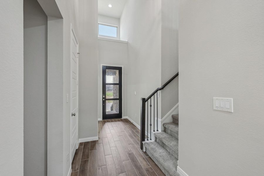Foyer entrance with dark wood-style flooring, baseboards, stairway, and a towering ceiling Foyer entrance with dark wood-style flooring, baseboards, stairway, and a towering ceiling