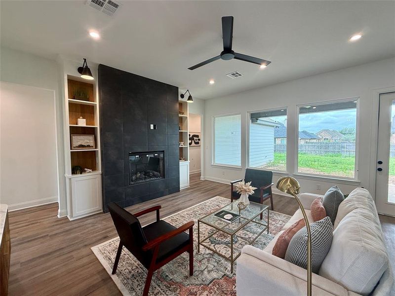 Living area featuring a floor-to-ceiling dark tile fireplace with an integrated firebox, flanked by built-in shelving units with lower cabinetry