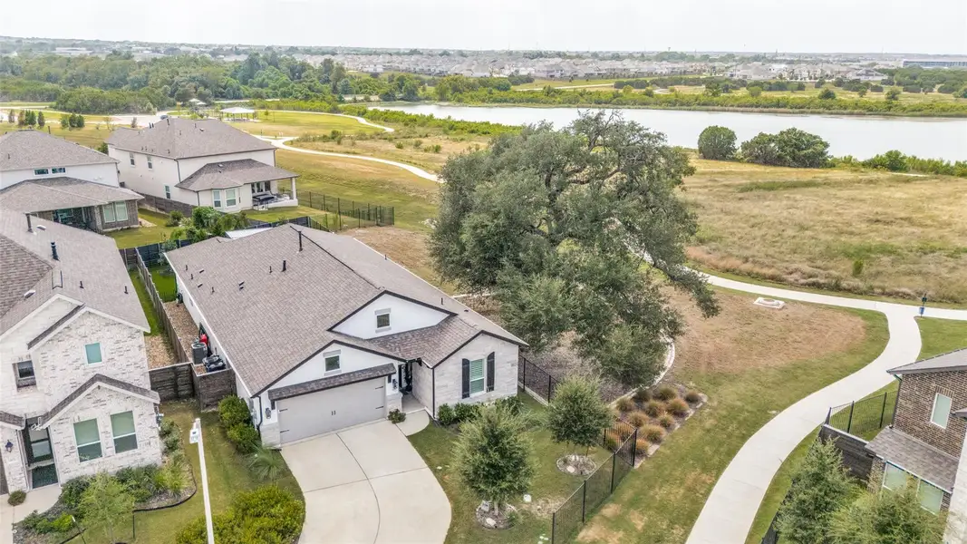 An aerial perspective showcases a modern single-story residence situated near a serene neighborhood lake.