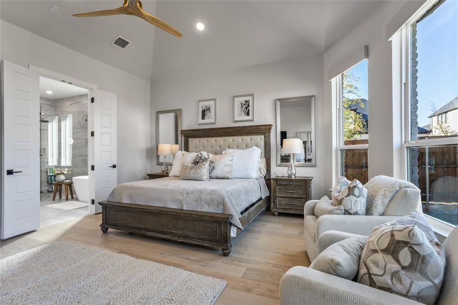 The primary suite has a wall of windows and plenty of room for a sitting area, with large double doors that lead to the luxurious ensuite bathroom