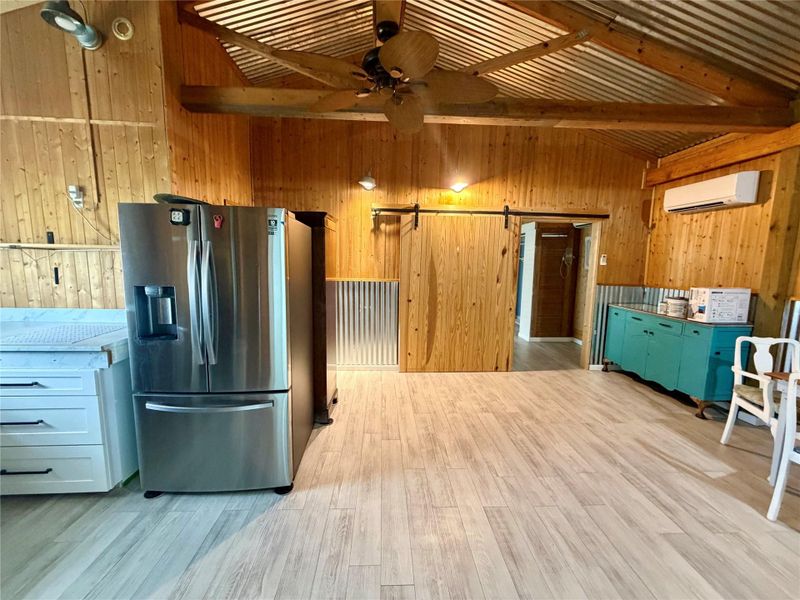 A spacious kitchen with rustic wood walls, vaulted ceilings, and modern appliances offers a unique aesthetic.