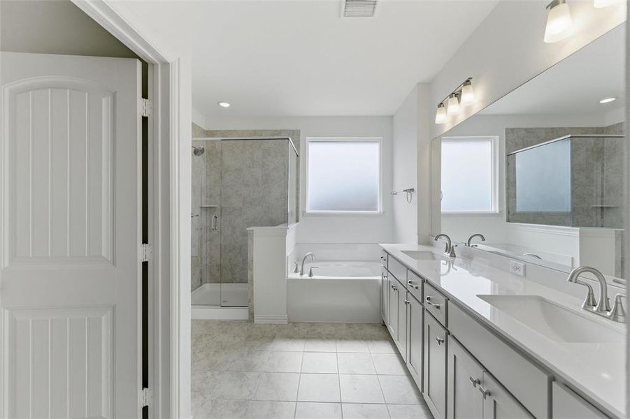 Full bath featuring a garden tub, double vanity, a shower stall, and light tile patterned floors