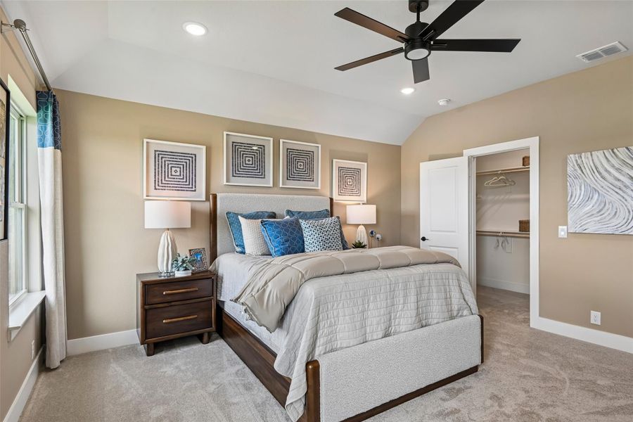 Bedroom with king bed, vaulted ceiling, ceiling fan, carpet floors, and walk-in closet entrance Bedroom with king bed, vaulted ceiling, ceiling fan, carpet floors, and walk-in closet entrance