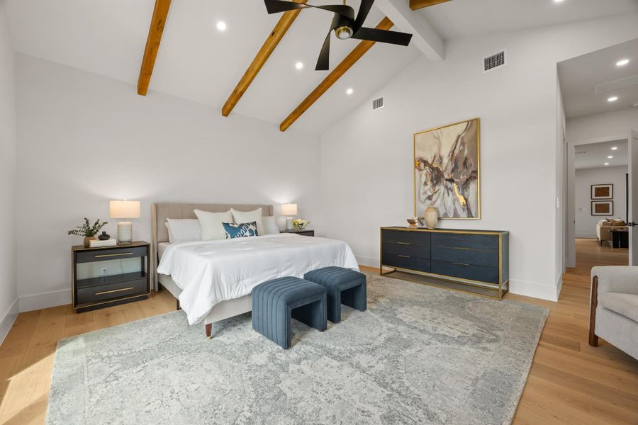 Exposed wood beams accentuate the soaring vaulted ceiling in this hardwood-floored bedroom.